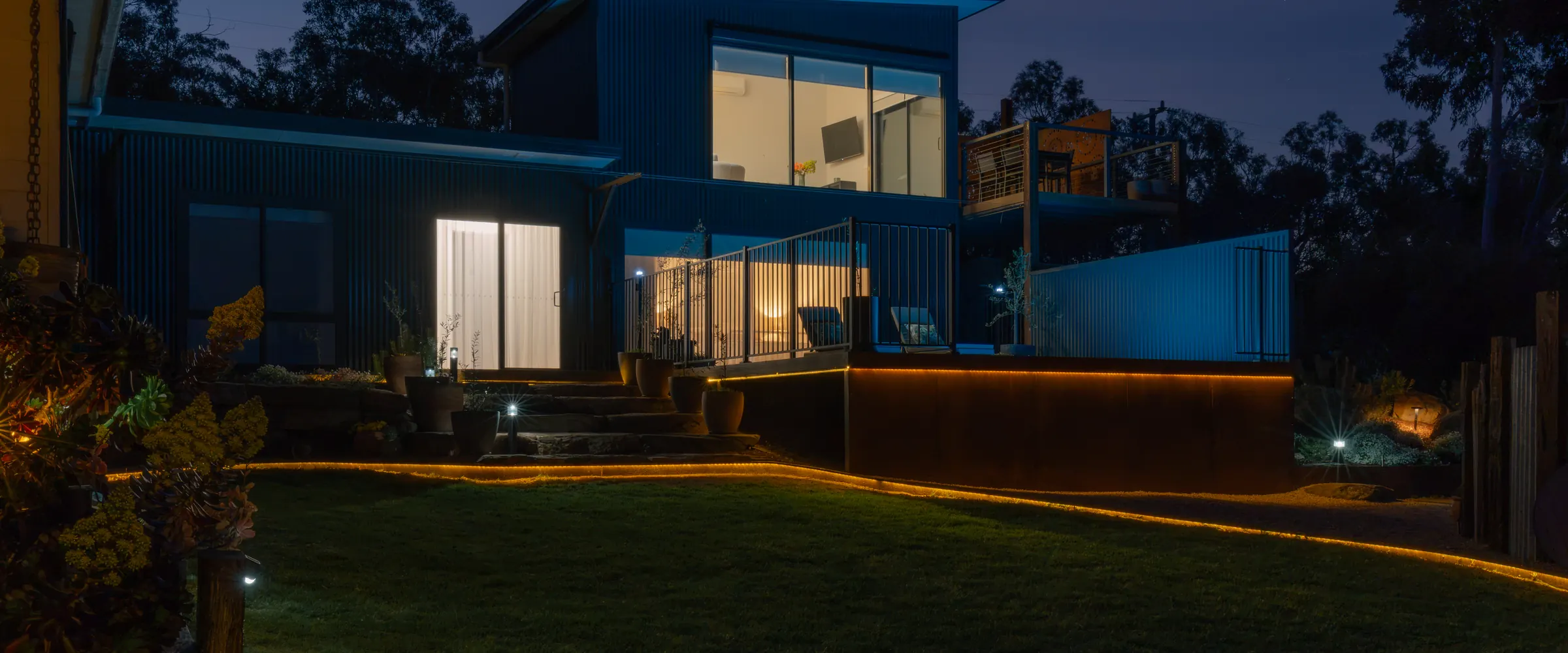 The accommodation at dusk, warm light in its windows and along the deck