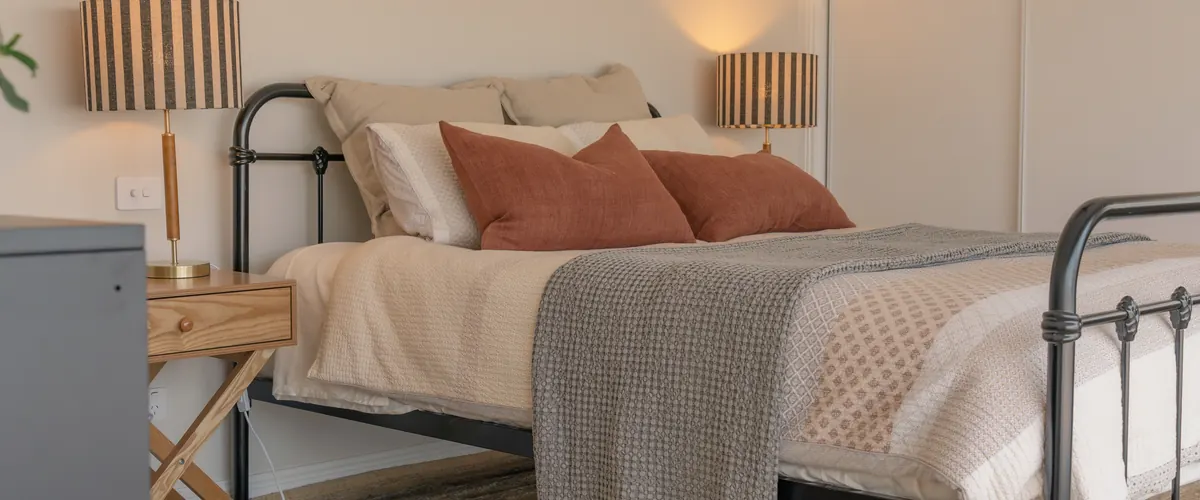 The bedroom, the bed made up with linen and a wall lamp either side