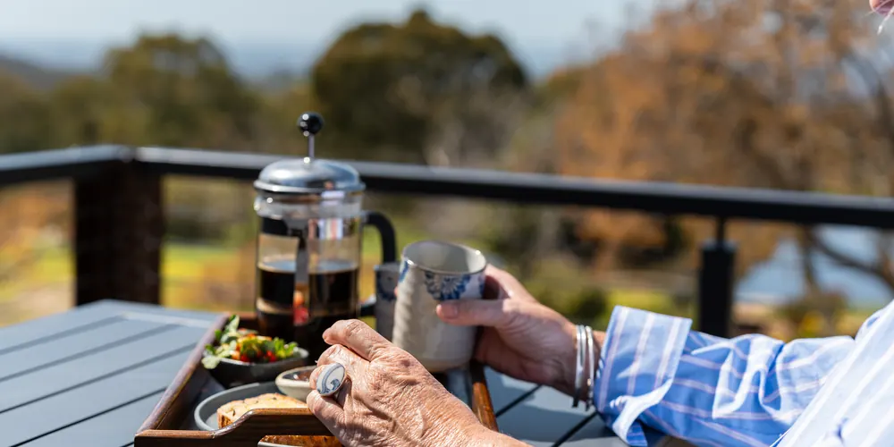 A coffee plunger and breakfast on the balcony rail, with the view beyond