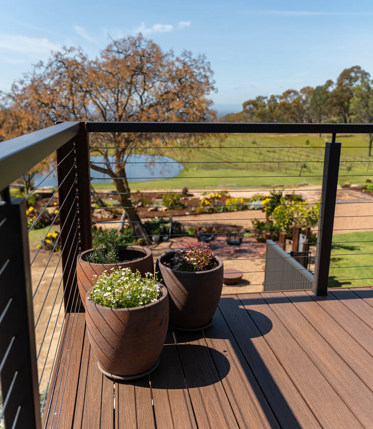 The balcony rail, looking past the potted plants over the dam and the vineyard
