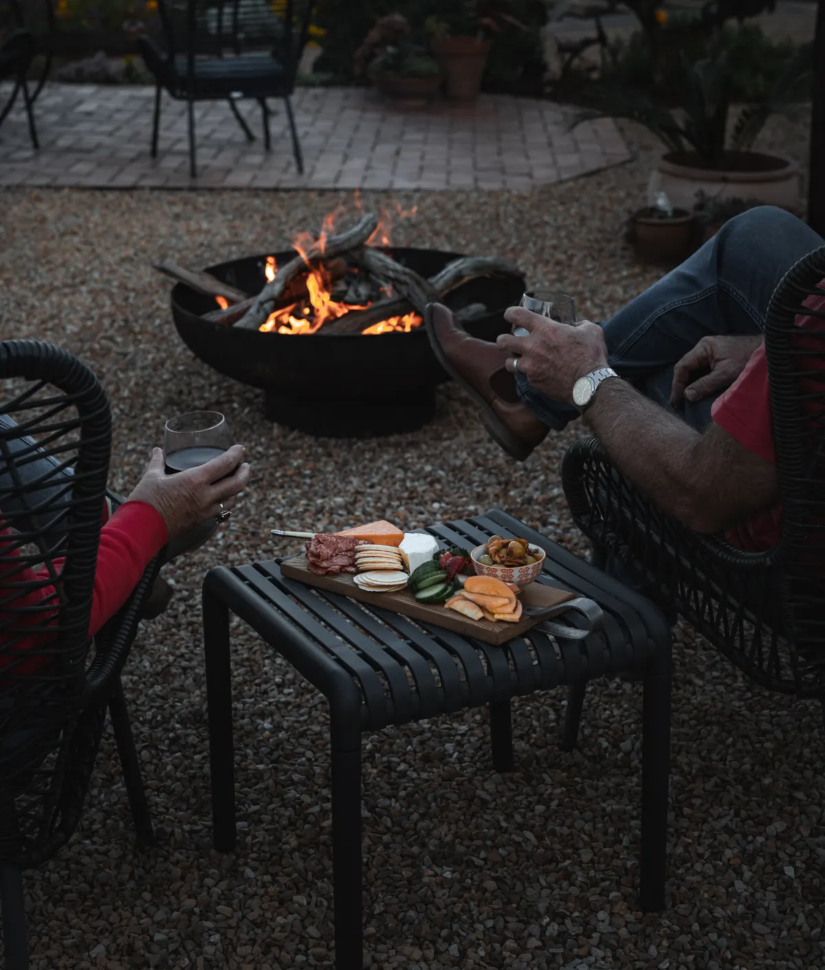 The fire pit burning at dusk, with chairs drawn around it
